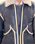 Male model detail shot, wearing our new Icarus style, a vintage-looking weathering grey colour flight jacket, 1/4 zipped showcasing stitched flap panel, off-white leather strips and body zipper.