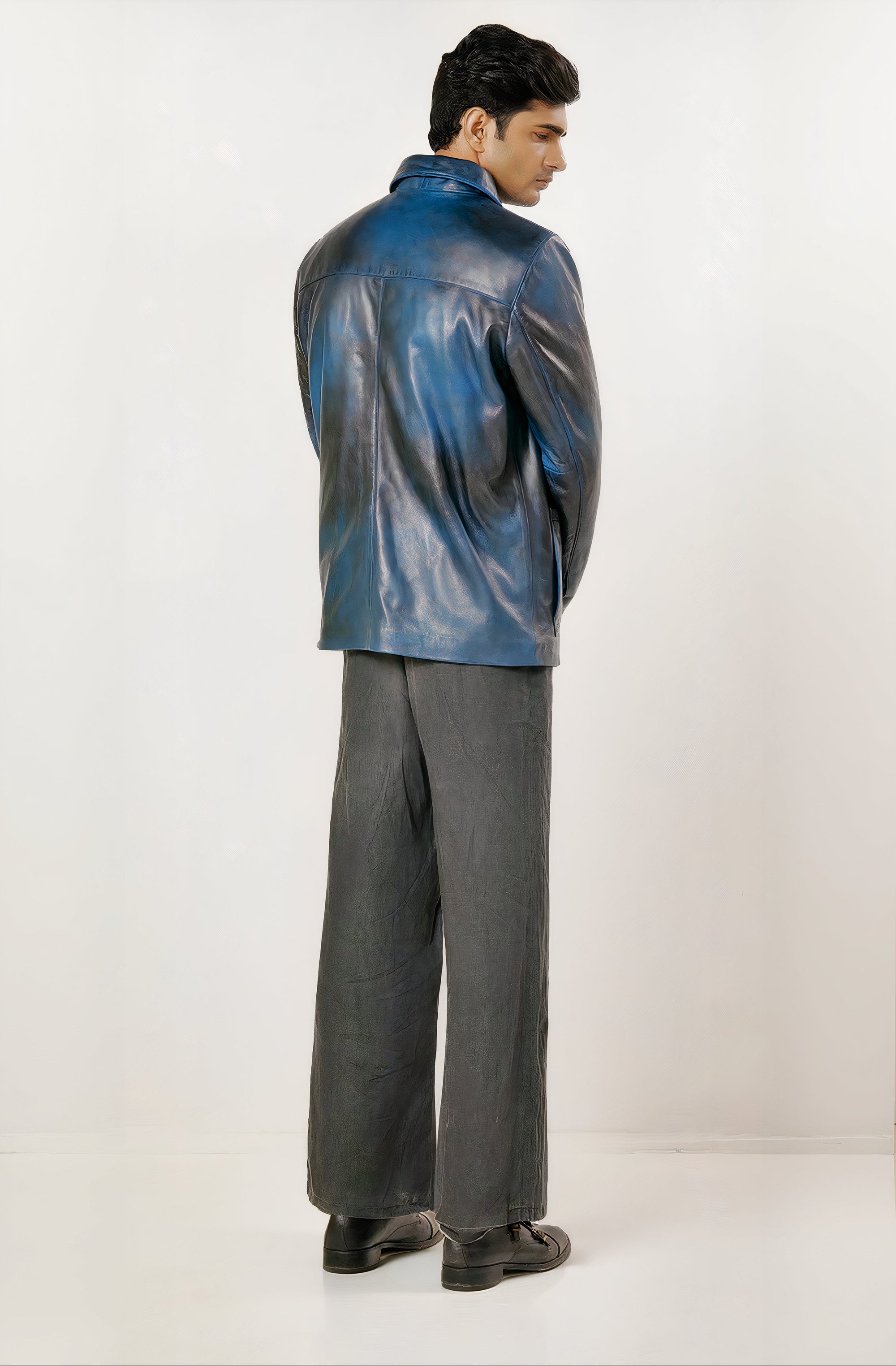 Male model full back shot, wearing our new Poseidon style, a two-tone black and blue chore jacket, wearing dark pants, dress shoes on a white background.