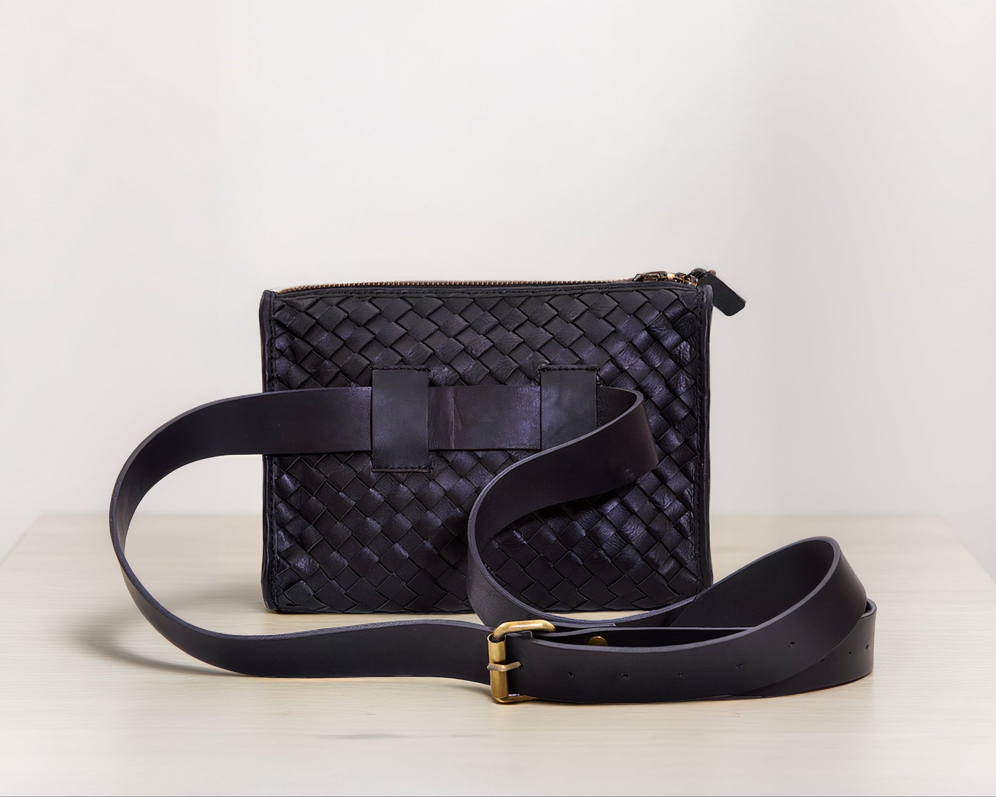 Back shot of our Apollo Loculus black woven belt bag showcasing the leather strap on a light background.