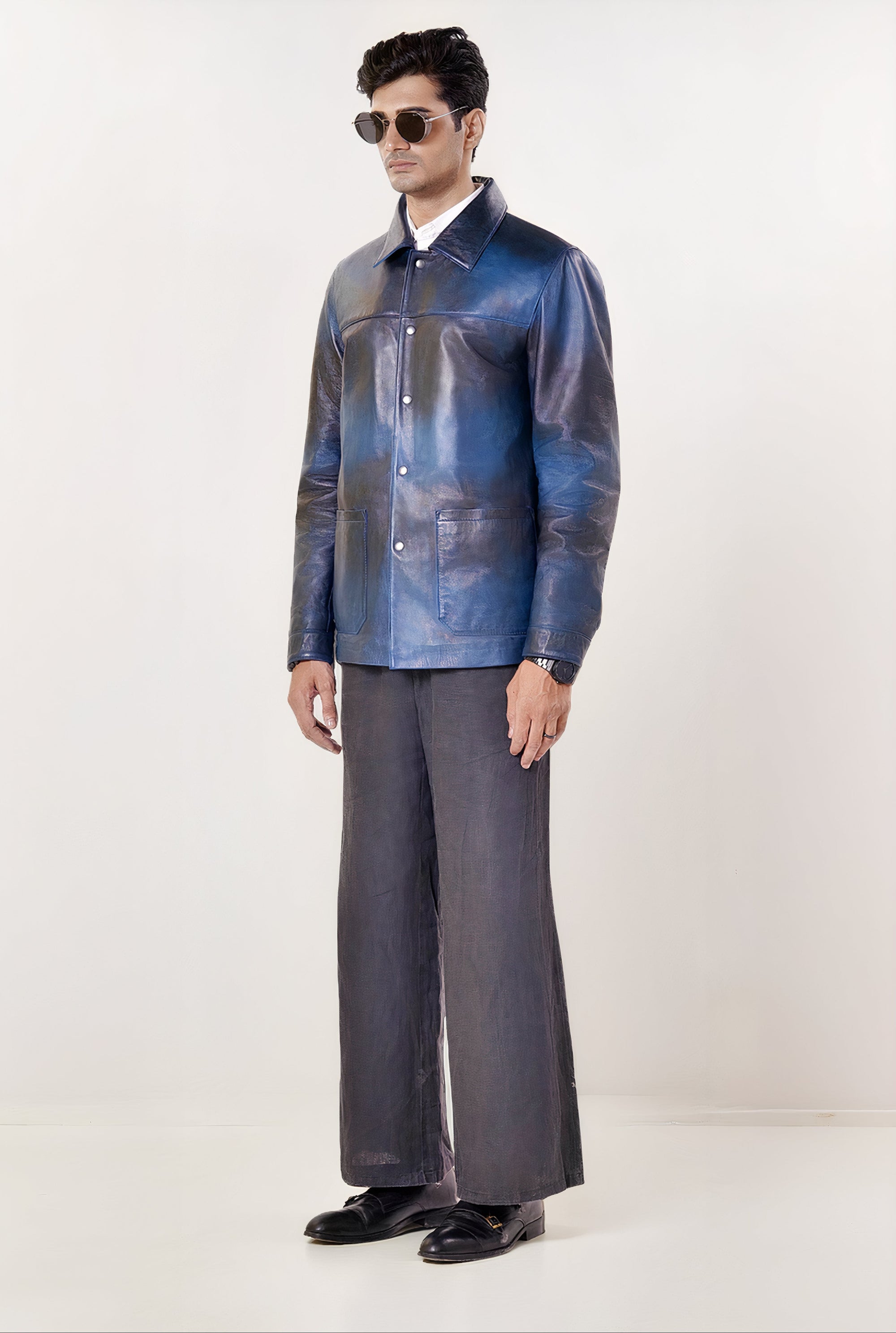 Male model full front shot, wearing our new Poseidon style, a two-tone black and blue chore jacket, fully buttoned up with silver snap buttons, wearing dark pants, dress shoes on a white background.