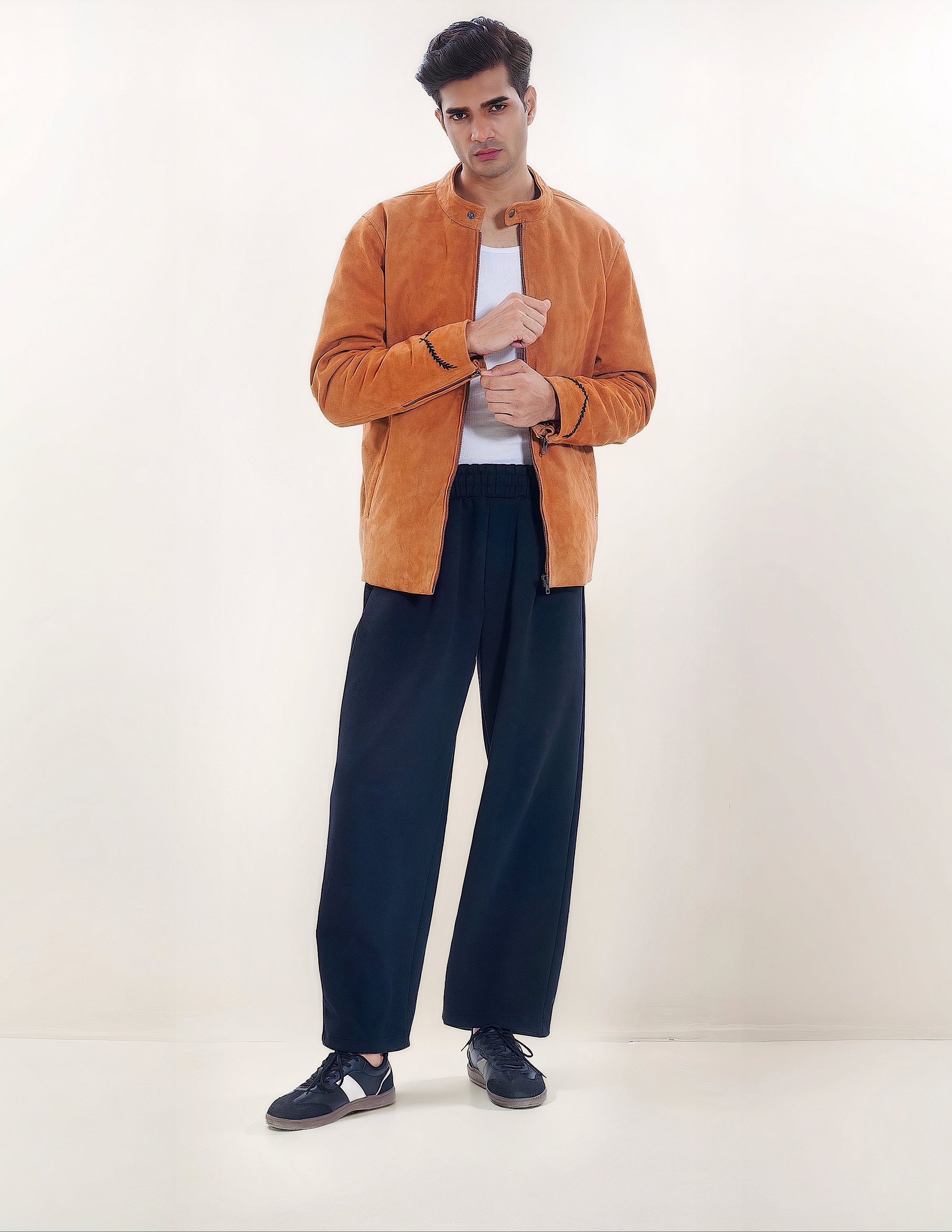 Male model full front shot, wearing our new Achilles style, a Tan suede/nubuck racer jacket showcasing embroidery detail, a white shirt, and dark pants on a white background.