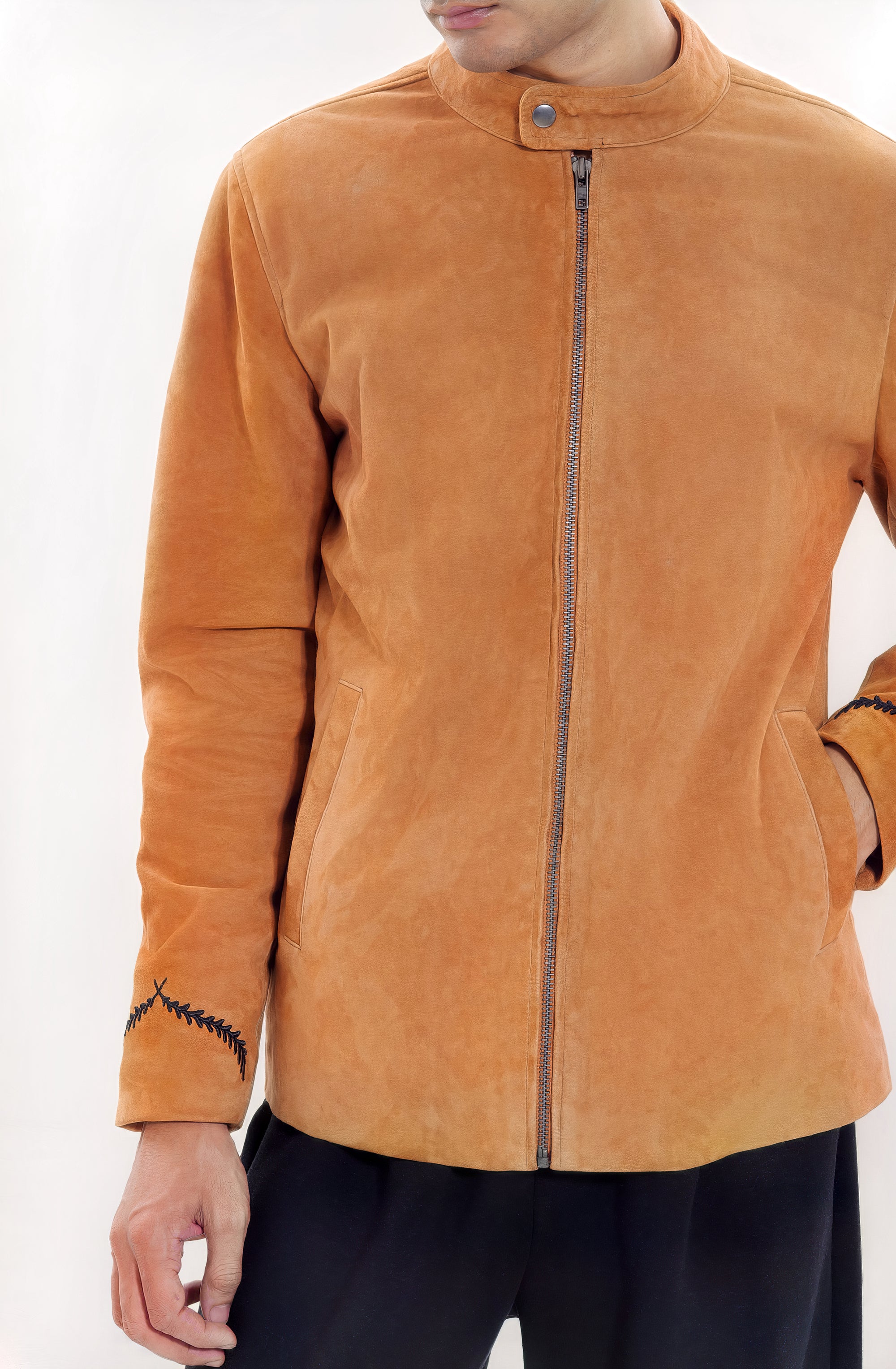Male model half front shot, wearing our new Achilles style, a Tan suede/nubuck racer jacket, zipped all the way up, showcasing embroidery detail, front body zip closure, and dark pants on a white background.